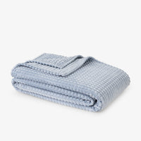 Folded light blue blanket on a white background