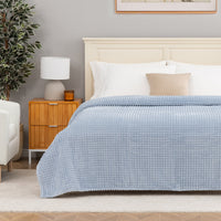 A blue waffle blanket decorated on a bed.