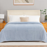 Blue waffle blanket decorated neatly on a bed.