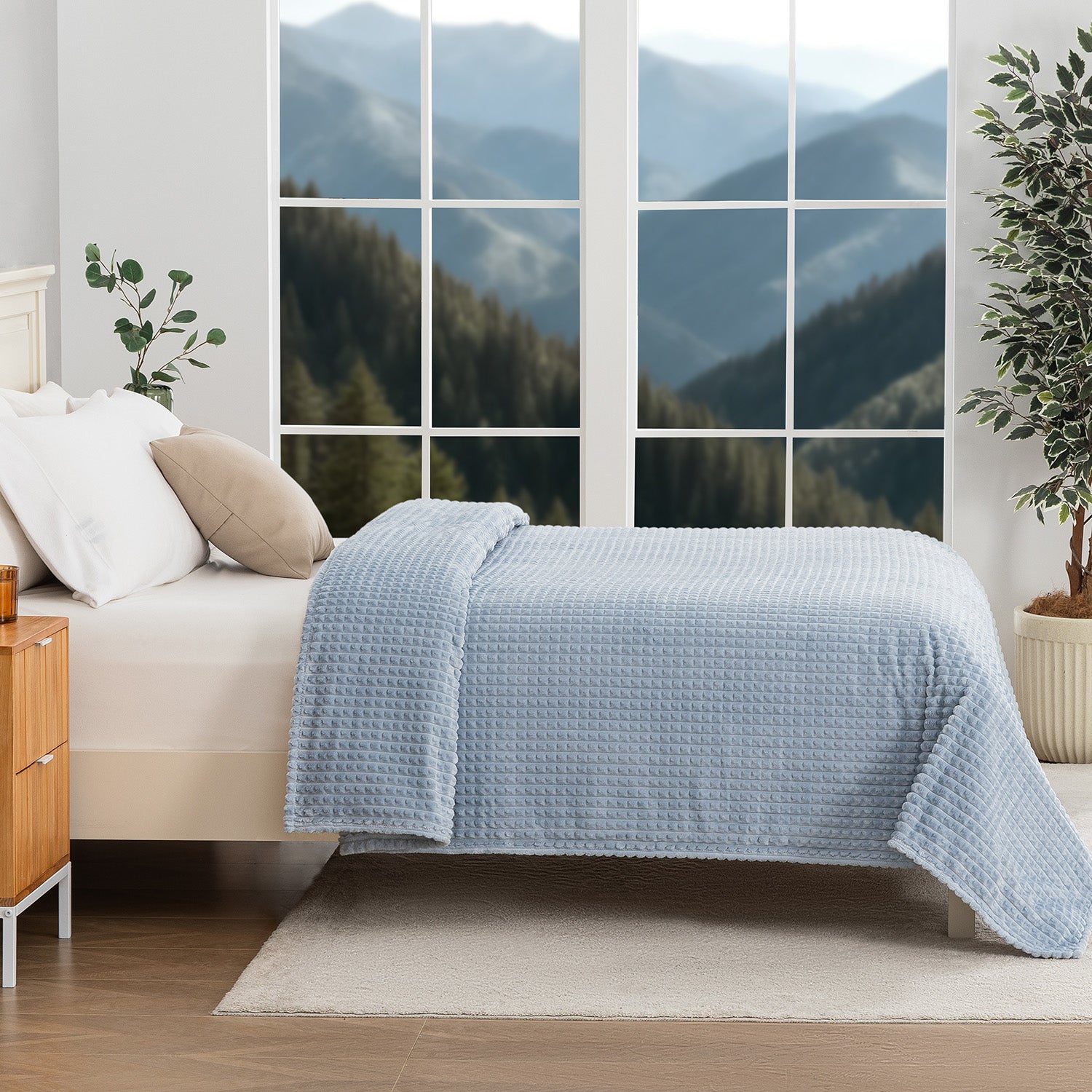 A blue waffle blanket decorated on a bed with a scenic background.