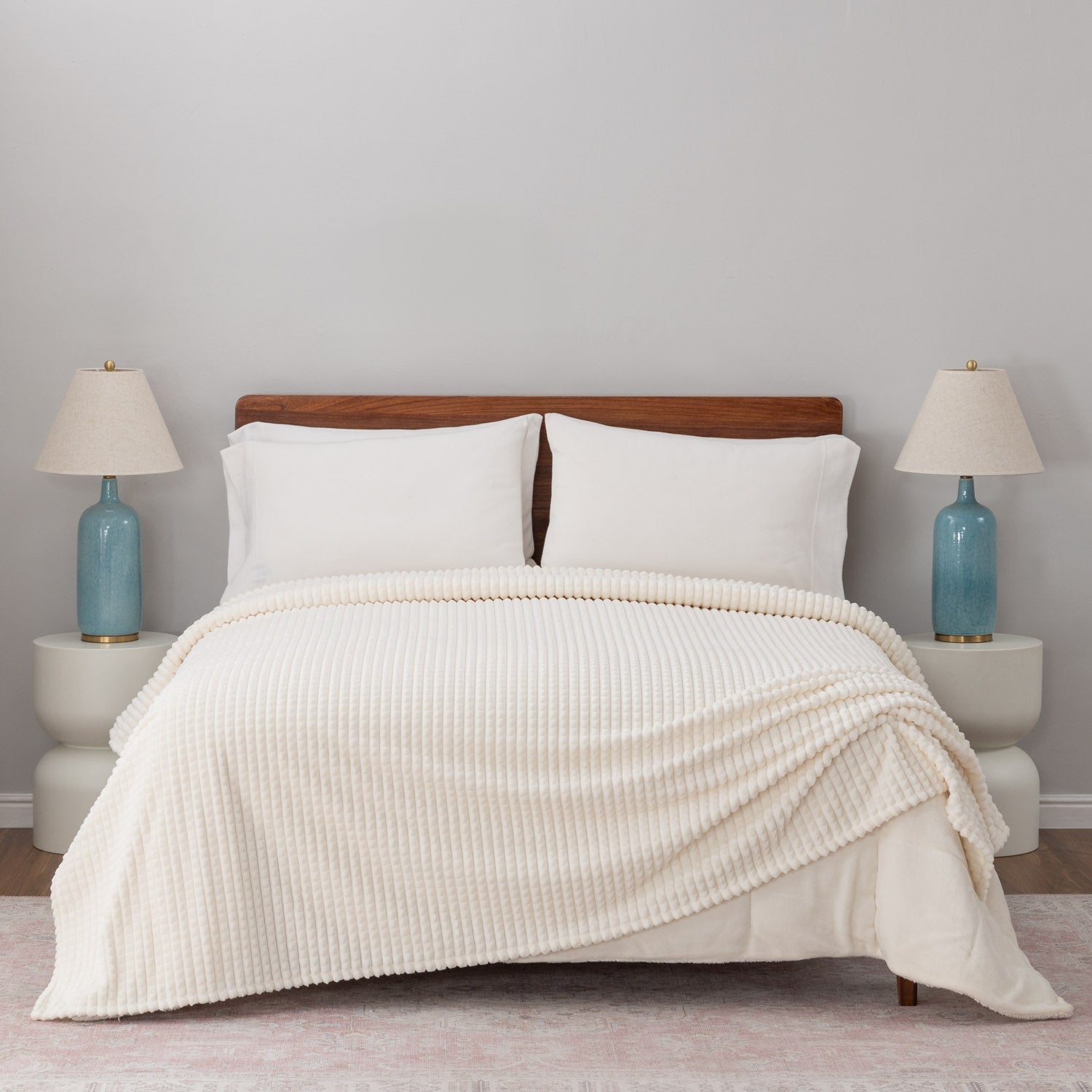 A cream VelvetLoft waffle blanket draped neatly on a white bed.