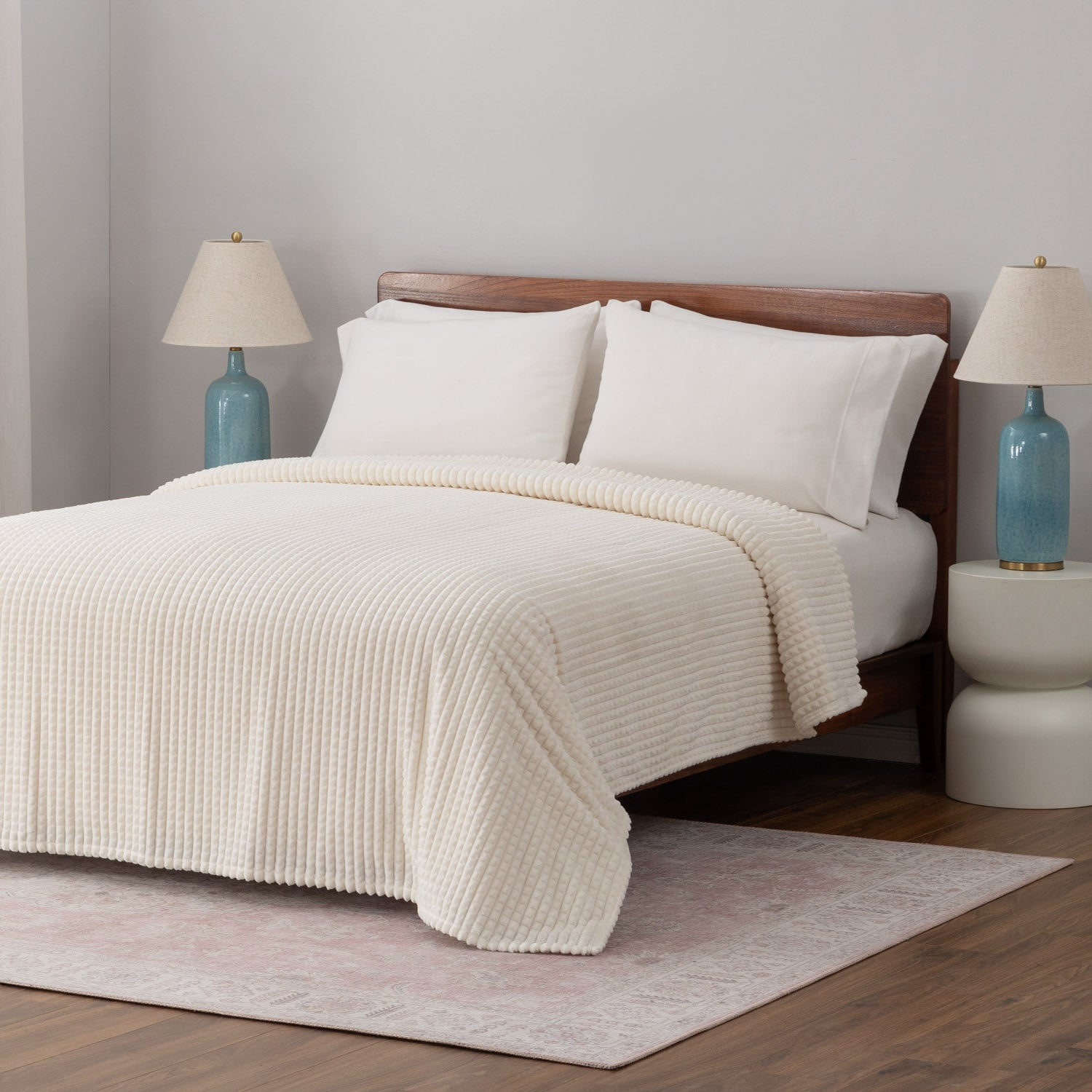 A cream VelvetLoft waffle blanket dressed neatly on a white bed.