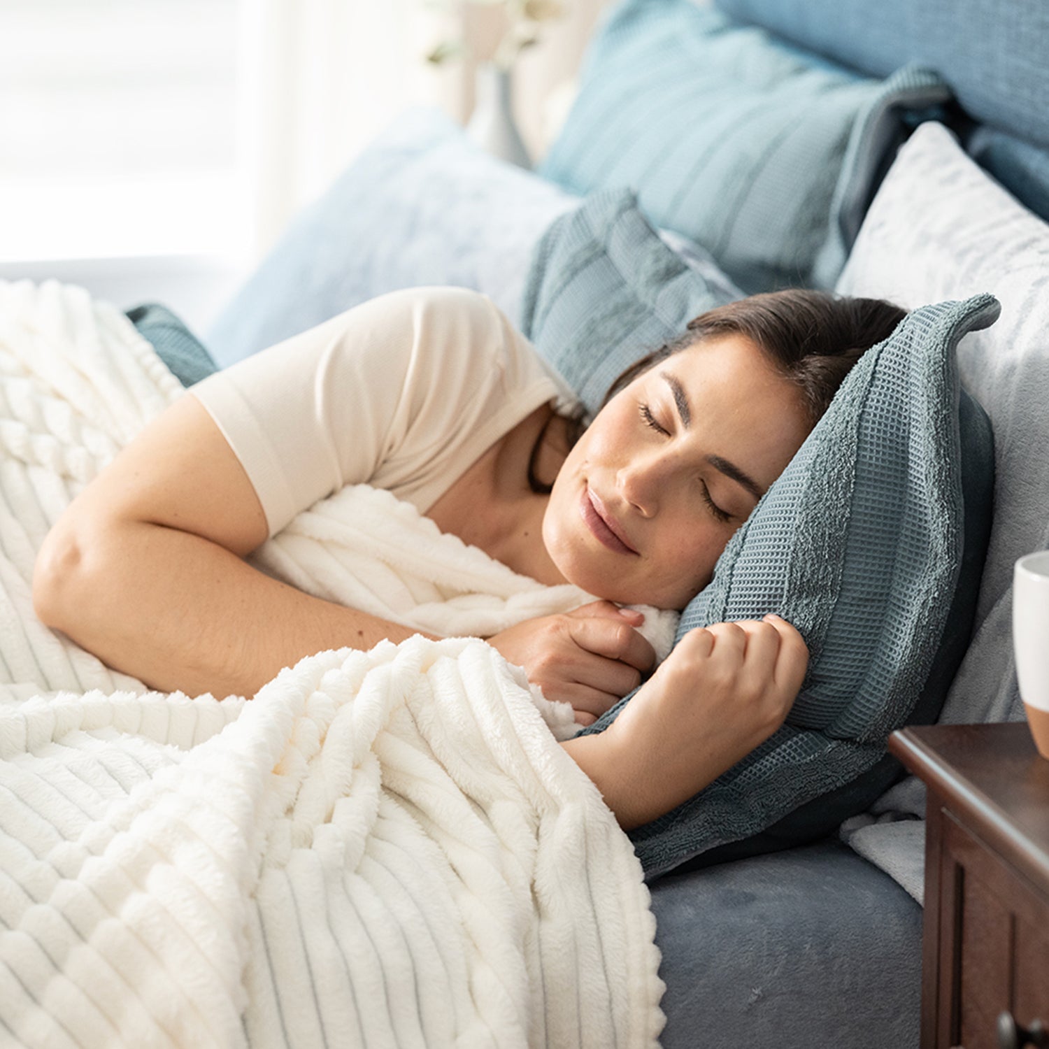 Woman sleeping in bed with a blue pillow and white blanket