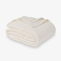 A cream VelvetLoft waffle blanket folded neatly on a white surface.