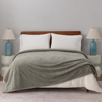 A sage green VelvetLoft waffle blanket draped neatly on a white bed.