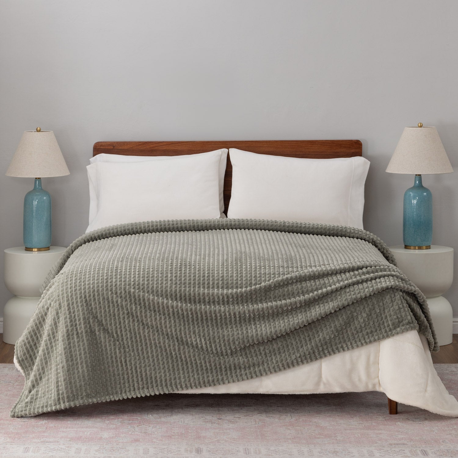 A sage green VelvetLoft waffle blanket draped neatly on a white bed.