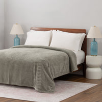 A sage green VelvetLoft waffle blanket laid neatly on a white bed.