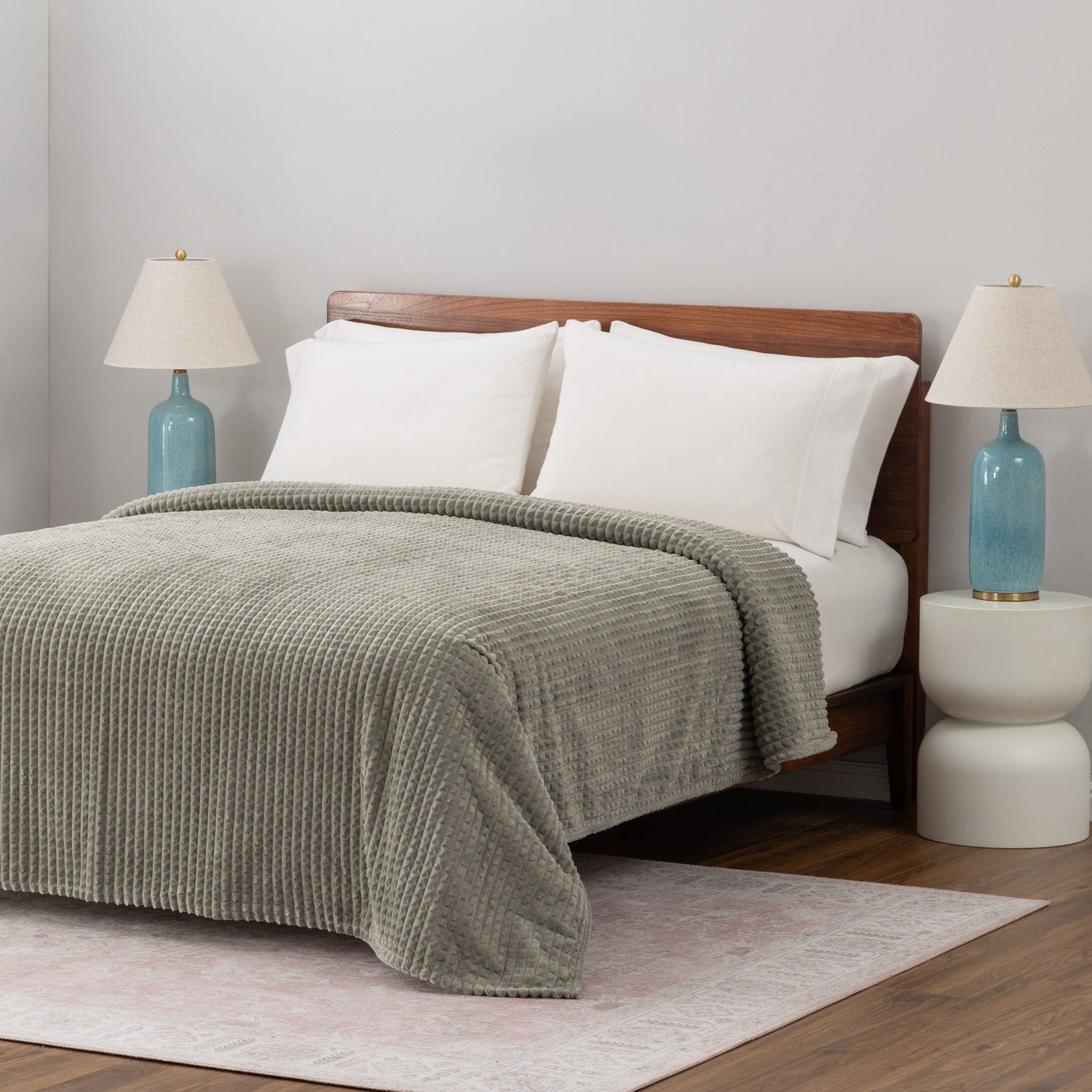 A sage green VelvetLoft waffle blanket laid neatly on a white bed.