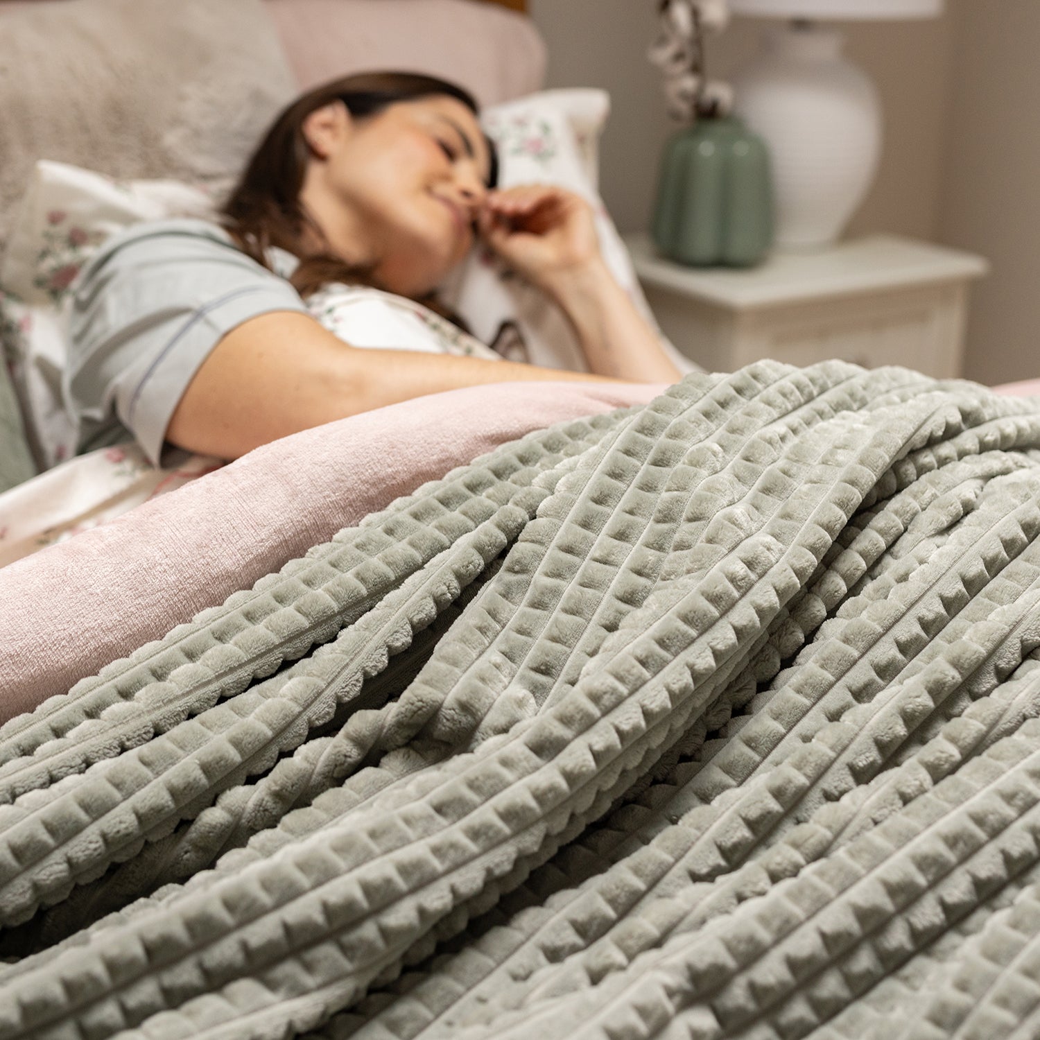 Person lying in bed with a textured blanket, blurred background