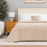 A tan waffle blanket decorated neatly on a bed.