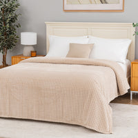 A tan waffle blanket decorated neatly on a bed.
