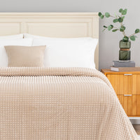 A tan waffle blanket decorated neatly on a bed.