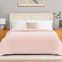 Pink textured blanket decorated neatly on a bed.