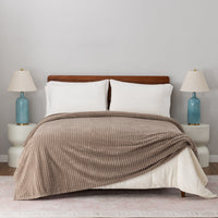 A brown VelvetLoft waffle blanket draped over a white bed.