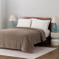 A brown VelvetLoft waffle blanket dressed neatly on a bed.