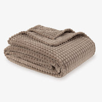 A brown VelvetLoft waffle blanket folded neatly on a white surface.