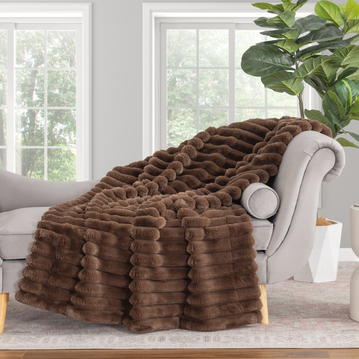 Brown faux fur throw blanket draped over a gray sofa in a living room.