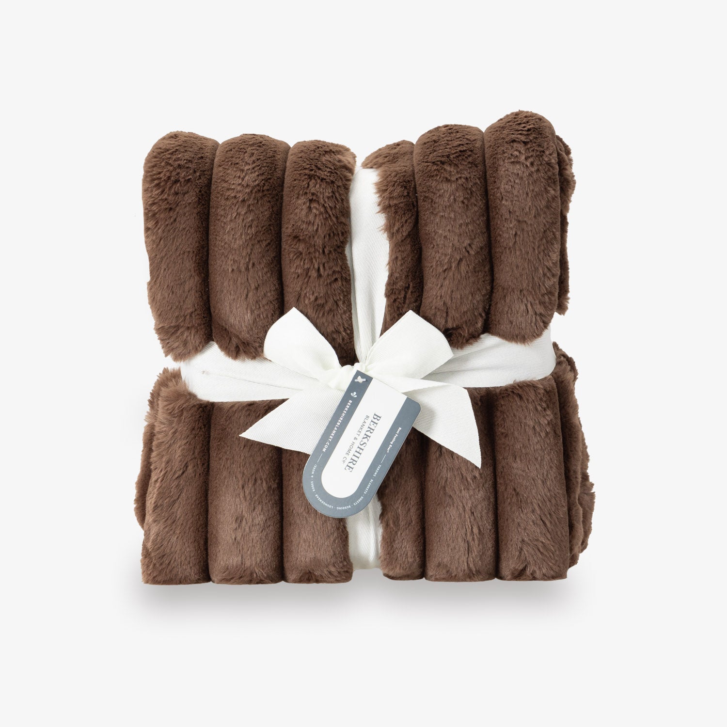 A brown textured throw with a white ribbon and tag on a white background