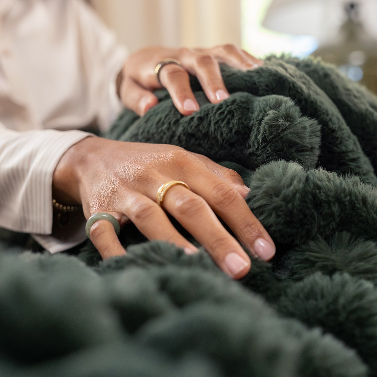 Close-up of hands with rings on a dark green textured fabric