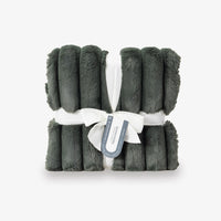 Green plush blanket with a white ribbon and label on a light gray background