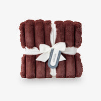 Red texture blanket tied with a white ribbon on a light gray background