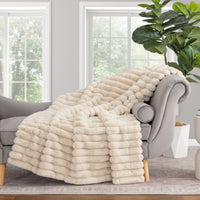 Beige blanket draped over a gray armchair in a room with large windows and a plant.