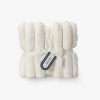 Folded white blanket with a tag on a light gray background