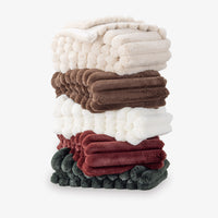 Stack of colorful textured throw blankets on a white background