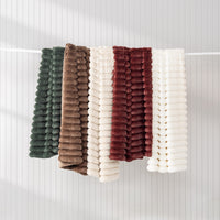 Set of five textured throws in green, brown, white, red, and white on a white background
