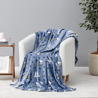A blue fleece throw blanket with a cartoon dog print is draped over a white armchair in a styled living room setting.