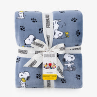 A folded light blue plush throw blanket with a Peanuts character print, wrapped in a white ribbon with the Peanuts logo and a yellow tag.