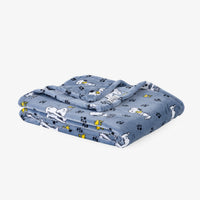 A folded blue blanket featuring a cartoon dog print and paw prints, displayed on a clean white background.