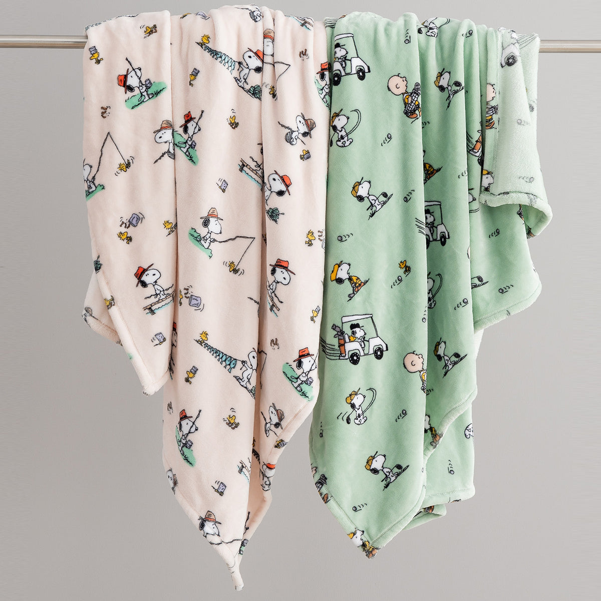 Two baby blankets with cartoon patterns on a gray background