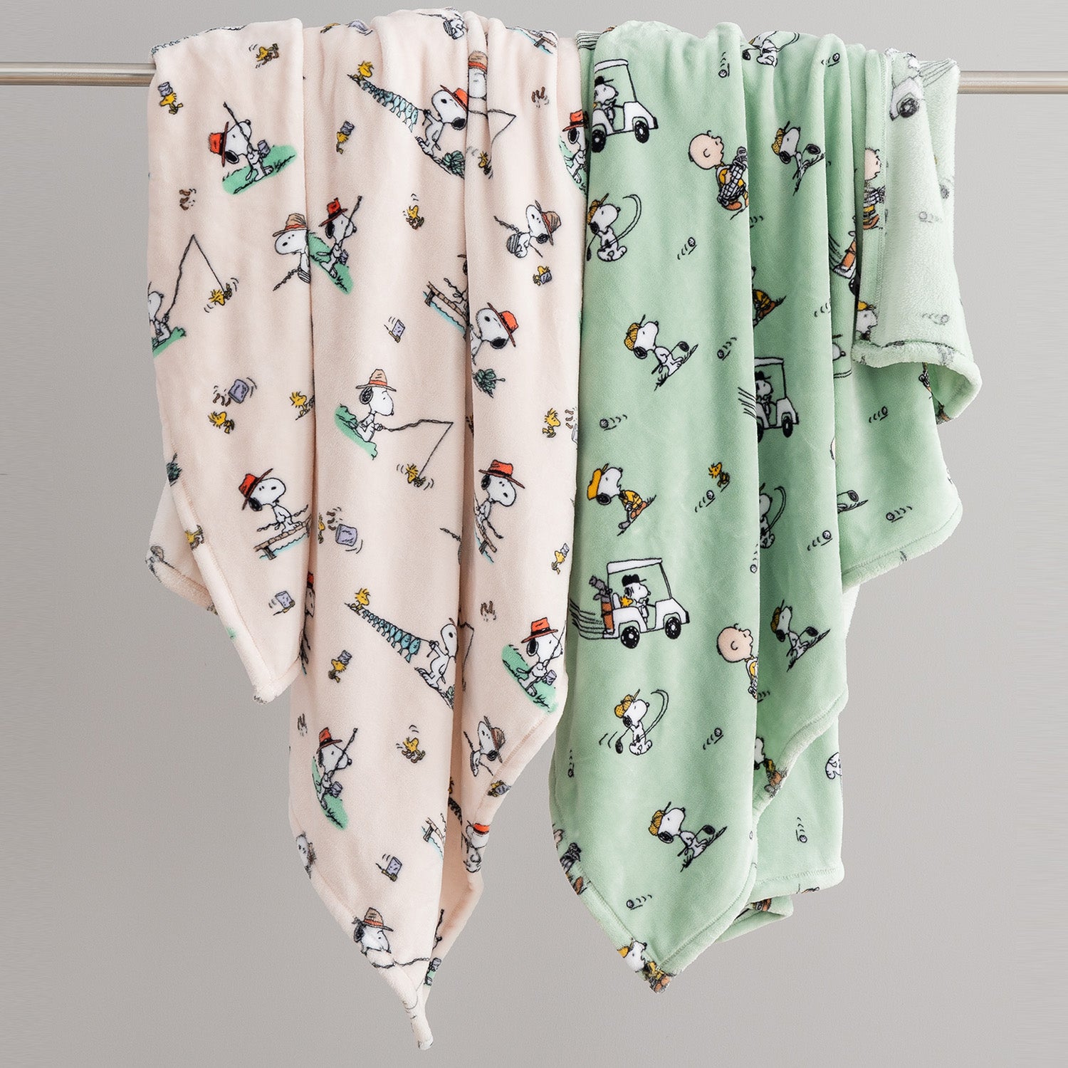 Two baby blankets with cartoon patterns on a gray background