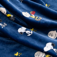 A close-up of a navy blue fabric featuring a repeating print of the Peanuts characters Snoopy, Woodstock, and Charlie Brown.