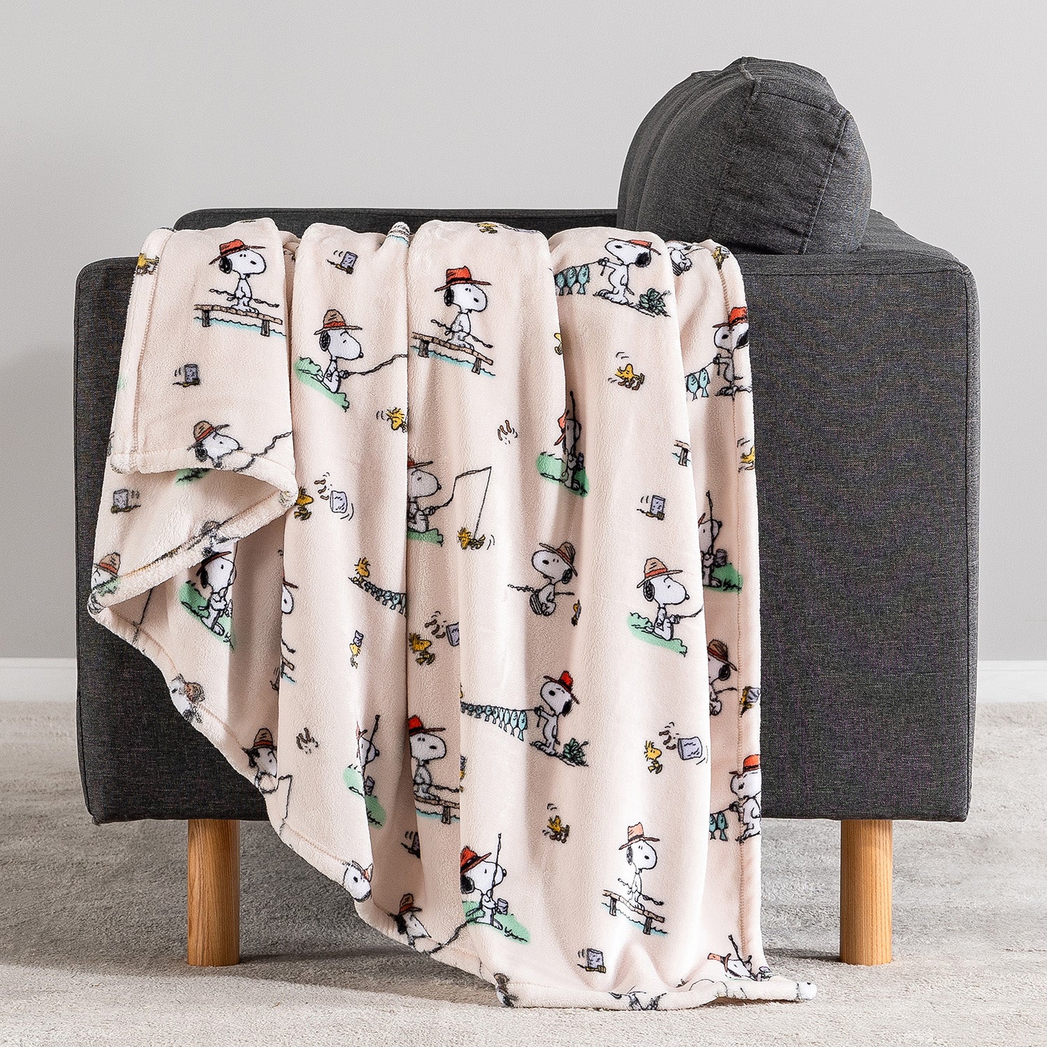 Blanket with cartoon character pattern draped over a gray chair.