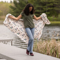 Woman holding a patterned blanket by a lake