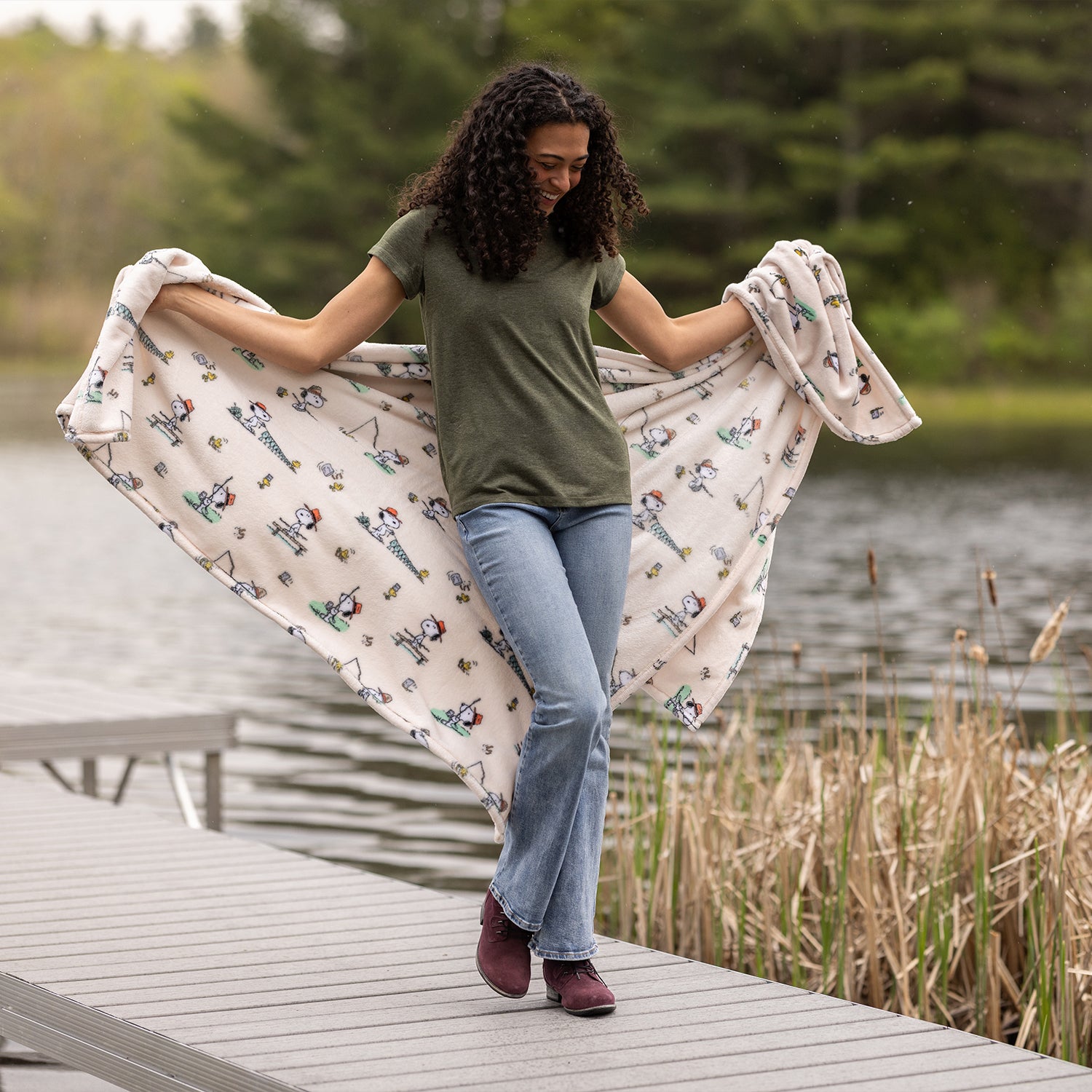Woman holding a patterned blanket by a lake