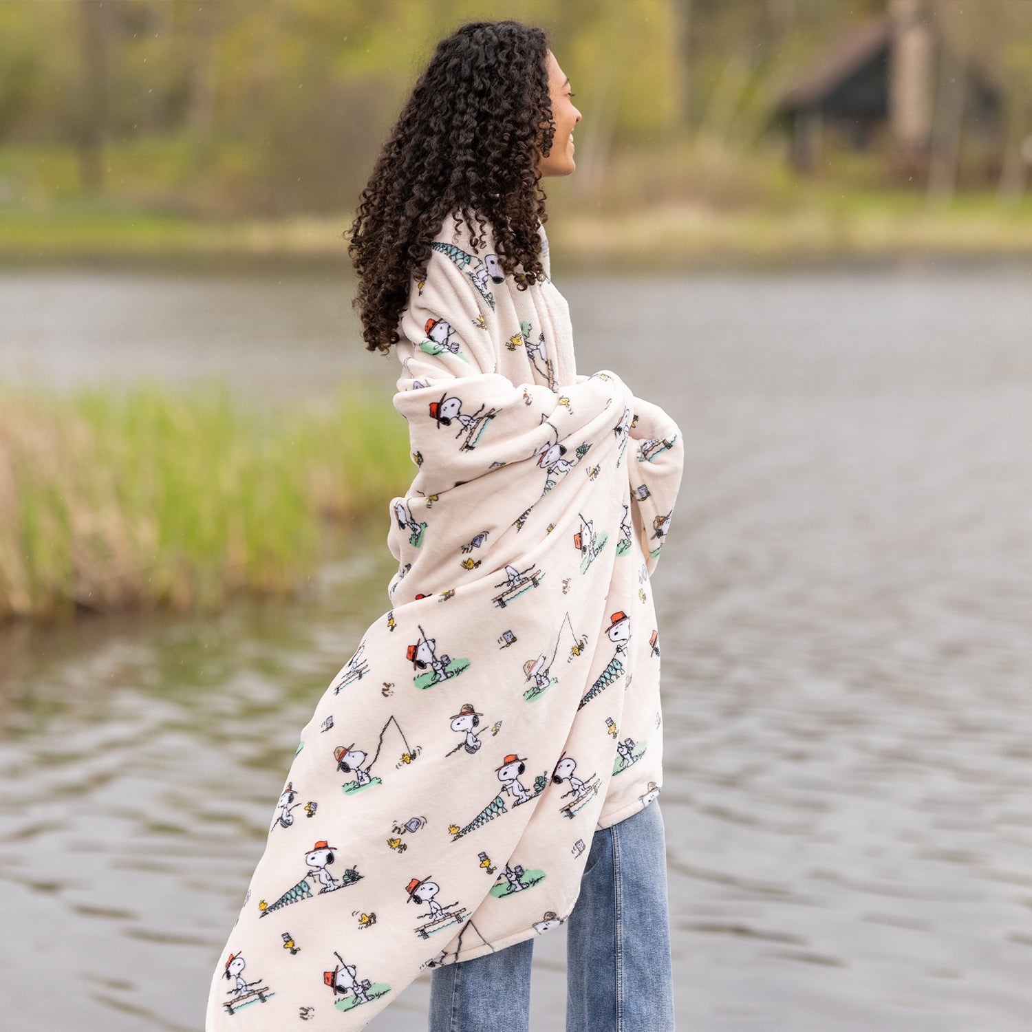 Woman wrapped in a patterned blanket standing by a lake