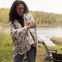Woman wrapped in a patterned blanket by a lake