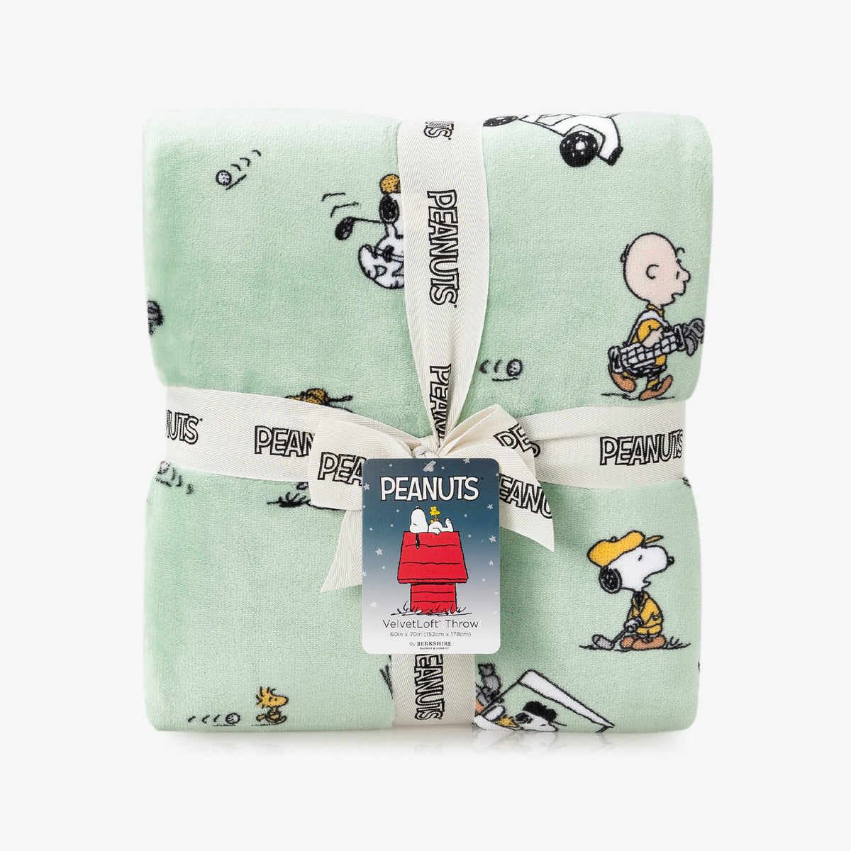 Folded green blanket with Peanuts character patterns and a visible tag on a white background