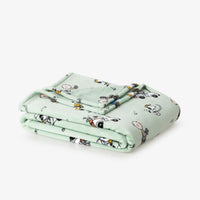 Folded light green blanket with cartoon characters on a white background