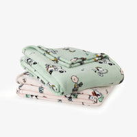 Stack of green and pink blankets with cartoon characters on a white background