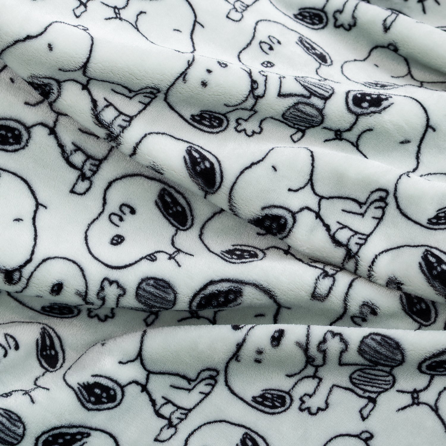 White plush fabric with an all-over black line-art print of Snoopy in various poses, shown in soft folds.