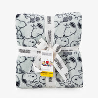A sage reen peanuts printed throw packaged neatly on a white surface.