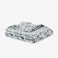A folded blanket featuring a black and white cartoon character pattern, displayed on a clean white background.