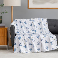 A white peanuts pritned throw draped over a grey sofa.