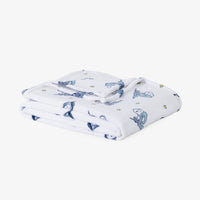A folded white muslin blanket with a blue white and star pattern, displayed on a clean white background.