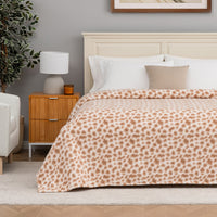 Bedroom with a bed featuring a leopard print blanket, nightstand, and lamp.