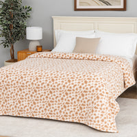 Bedroom with a bed covered in a leopard print blanket, nightstand, and lamp.